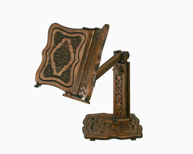 May include: A wooden book stand with intricate carvings. The stand is adjustable and has a dark brown finish.