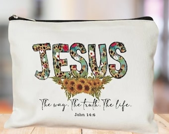 May include: A white canvas zippered pouch with the word "JESUS" in a floral and leopard print design. Below the word "JESUS" is a bouquet of sunflowers. The text "The way. The truth. The life. John 14:6" is printed below the flowers. The words "JOYOUS WORDS" are printed above.