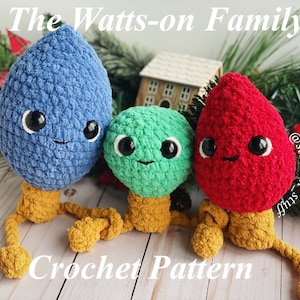 Puede incluir: Patrón de crochet para una familia de tres adornos de bombilla. Los adornos son azules, verdes y rojos y tienen caras lindas. El patrón se llama "The Watts-on Family".