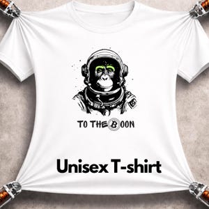 May include: White unisex t-shirt featuring a black and white illustration of a chimpanzee astronaut wearing a helmet. The text "TO THE MOON" and "Unisex T-shirt" are printed below the graphic.