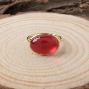 以下が含まれることがあります： 大きな楕円形の赤い宝石が付いた金の指輪
