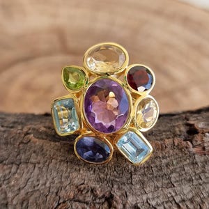 May include: A gold ring with a cluster of colorful gemstones, including amethyst, citrine, peridot, aquamarine, and garnet.
