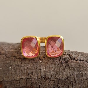 May include: Gold ring with two pink square-shaped gemstones.