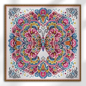 Może przedstawiać: Oprawiony wzór haftu krzyżykowego z symetrycznym wzorem motyla. Motyl składa się z żywych kolorów, w tym różowego, niebieskiego, żółtego i pomarańczowego. Wzór jest na białym tle i oprawiony w jasnobrązową ramę.