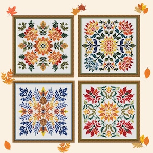 May include: Four framed cross-stitch patterns with floral designs in shades of orange, yellow, red, blue, and green. Each square artwork features a symmetrical, detailed flower or leaf pattern. The frames are a warm brown colour, and the background is a light beige.