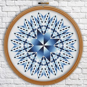 May include: A blue and white geometric star pattern cross stitch design in a wooden embroidery hoop.