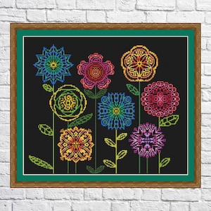 May include: A framed cross-stitch embroidery featuring a colourful floral design on a black background. The flowers are stylised and geometric, with vibrant colours like red, orange, yellow, green, blue, and purple.