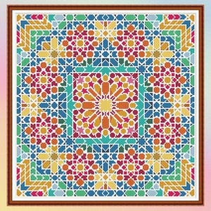 May include: A framed, colorful cross-stitch pattern featuring a geometric design. The artwork showcases a symmetrical arrangement of shapes in shades of orange, yellow, blue, green, and red. The piece is framed in a brown wooden frame.
