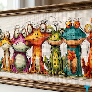 Può includere: Opera d'arte a punto croce raffigurante una fila di rane colorate e stravaganti. Le rane sono in varie tonalità di arancione, verde, viola e blu, con grandi occhi espressivi. L'opera è incorniciata in una cornice di legno marrone.