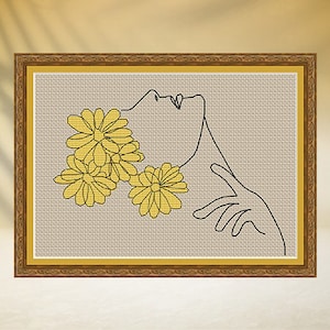 May include: A line drawing of a person's face with yellow flowers around the head. The drawing is on a beige background and framed in a brown frame.
