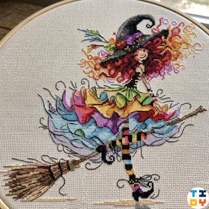 Puede incluir: Bordado de punto de cruz de una bruja caprichosa montada en una escoba. La bruja tiene pelo rojo, un sombrero negro y un vestido colorido. La escoba es marrón, y el fondo es una tela neutra en un bastidor de madera. Imagen artesanal colorida y detallada.