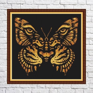 Könnte beinhalten: Ein goldener Schmetterling mit filigranen Details, der einem Tigergesicht ähnelt, vor schwarzem Hintergrund.