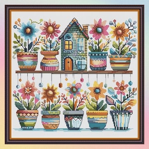 Può includere: Un disegno a punto croce con una casa e diversi fiori in vaso. I fiori sono di vari colori, tra cui blu, rosa, giallo e arancione. I vasi hanno motivi colorati. Il disegno è incorniciato da un bordo marrone scuro.