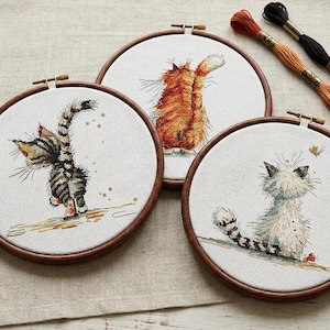 Könnte beinhalten: Ein Set aus drei Keramikbechern mit gesprenkelter, matter Oberfläche. Jeder Becher hat eine andere Farbe: hellblau, creme und grau. Die Becher haben ein schlichtes, modernes Design und einen bequemen Griff.