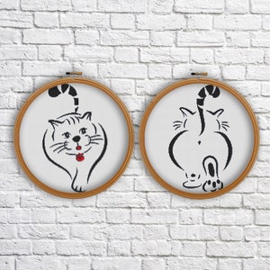 Pode incluir: Duas ilustrações de gatos em preto e branco em aros de bordado. Um gato está olhando para a frente com uma boca vermelha, o outro está olhando para trás com o rabo enroscado.