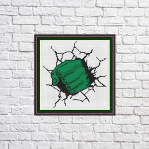 May include: A green fist breaking through a white brick wall. The fist is green and has a detailed design. The wall is white with cracks.