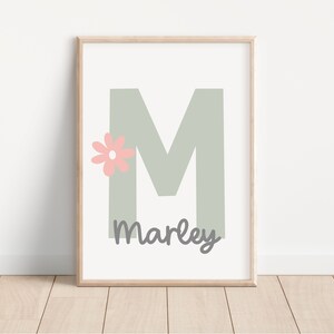 May include: A printable wall art design featuring a large, light green letter M with a pink flower and the name "Marley" written below.