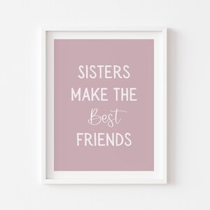 May include: A dusty rose pink printable wall art print with white text that reads "Sisters make the best friends".