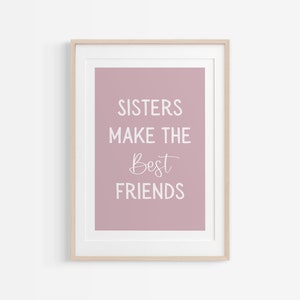 May include: A framed print with a pink background and white text that reads "Sisters make the best friends".