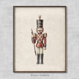 May include: A watercolour illustration of a traditional wooden nutcracker soldier in a red and gold uniform, holding a spear. The nutcracker is standing against a white background with the text "Grace Galerie" at the bottom.
