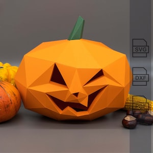 Può includere: Una zucca di carta arancione con un viso di zucca intagliato. La zucca è appoggiata su una superficie grigia con altre decorazioni autunnali, tra cui mais e castagne.