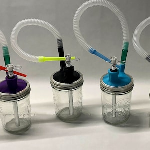 May include: Four glass jars with colorful lids and clear plastic tubes attached. Each jar has a different colored lid: purple, black, blue, and red. The tubes are connected to a mouthpiece and a small bowl.