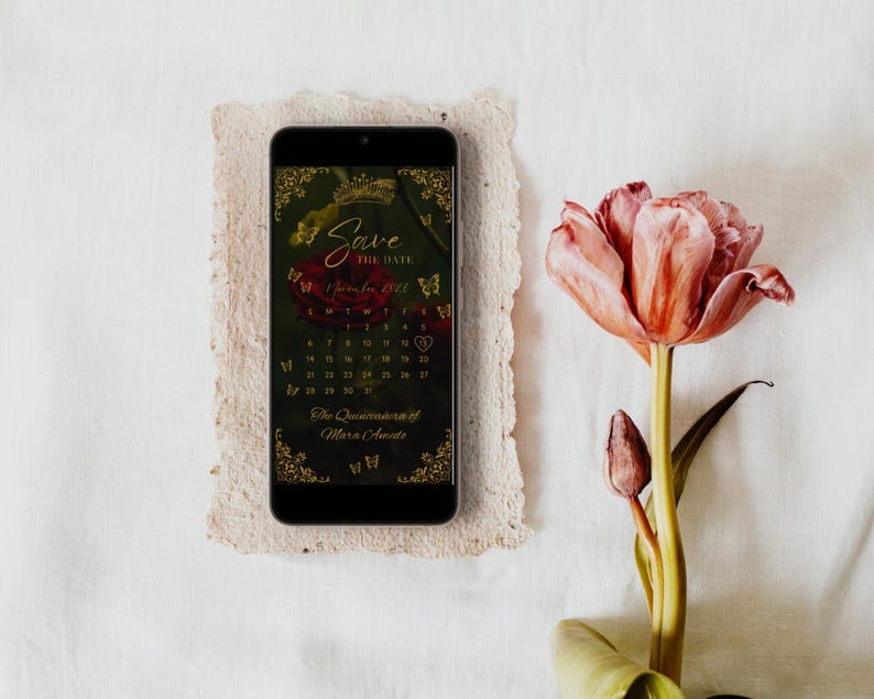 May include: A smartphone displaying a digital Save the Date calendar for November 2022, featuring a dark background with a red rose, gold butterfly accents, and the text The Quinceanera of Mara Amado, positioned next to a pink tulip.