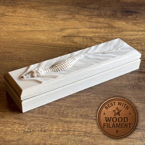 Peut inclure: Une bo&icirc;te rectangulaire en bois clair avec une sculpture d&eacute;taill&eacute;e d'hippocampe sur le couvercle. L'hippocampe est en relief, cr&eacute;ant un effet 3D. La bo&icirc;te est ferm&eacute;e et repose sur une surface en bois. Un embl&egrave;me circulaire indique "BEST WITH WOOD FILAMENT."