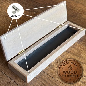 Peut inclure: Bo&icirc;te en bois ouverte avec int&eacute;rieur noir et charni&egrave;res en laiton. La bo&icirc;te est rectangulaire et a une finition en bois clair. Une petite pile d'aimants, environ 4x2cm, est montr&eacute;e. Le texte "BEST WITH WOOD FILAMENT" est sur un embl&egrave;me en bois.