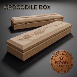 Könnte beinhalten: Zwei hellbraune Holzkisten mit einem geschnitzten Krokodil-Design auf den Deckeln. Die Kisten sind rechteckig. Der Text "CROCODILE BOX" steht oben. Ein Holzmedaillon unten zeigt "BEST WITH WOOD FILAMENT".