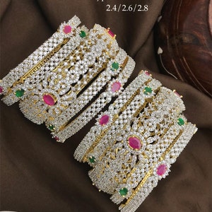 Peut inclure: Un ensemble de sept bracelets en or avec des motifs complexes, ornés de pierres en zircone cubique claires et roses, et des accents verts. Les bracelets sont empilés les uns sur les autres, créant un look superposé. Le texte "Nj 381 Premium quality Gj polish Ad stones 2.4/2.6/2.8" est visible sur l'image.