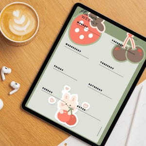 Könnte beinhalten: Ein digitales Tablet mit einer Wochenplaner-Vorlage auf hellgrünem Hintergrund. Das Layout enthält den Text Planner Weekly, die Wochentage sowie Illustrationen einer Erdbeere, Kirschen und eines kleinen Hasen, der Kirschen hält.