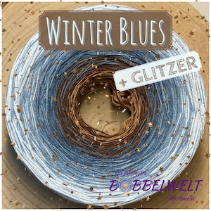 Könnte beinhalten: Garnknäuel mit Farbverlauf in Blau- und Brauntönen, beschriftet mit "Winter Blues + Glitzer". Goldfarbene Sternkonfetti umgeben das Garn. Produkt von "Die fabelhafte Bobbelwelt der Amelie".