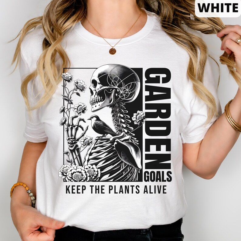 May include: White t-shirt with a black and white graphic of a skeleton holding flowers and a bird. The text "GARDEN GOALS KEEP THE PLANTS ALIVE" is printed on the shirt.