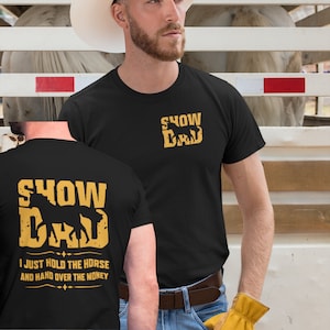 May include: Black t-shirt with a gold silhouette of a horse and the text "Show Dad" on the front. The back of the shirt has the same design with the text "I just hold the horse and hand over the money."