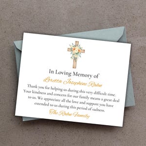 May include: A white card with text, "In Loving Memory of Loretta Josephine Rahn," and a floral cross illustration. The card is inside a pale blue envelope, with text thanking for support during a difficult time.