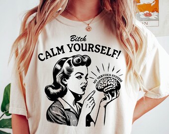May include: A white t-shirt with a black graphic of a woman pointing at a brain with the text "Bitch Calm Yourself! My Nervous System"