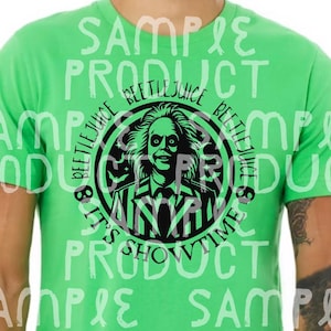 May include: A lime green t-shirt featuring a black and white graphic of Beetlejuice from the movie. The graphic is circular and includes the text "BEETLEJUICE" and "IT'S SHOWTIME". The shirt is a short-sleeved crew neck.