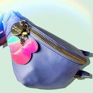 May include: A light purple fanny pack with a gold zipper and a holographic pink and blue Mickey Mouse charm.