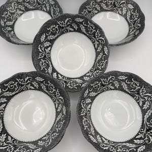 May include: Five white and gray patterned bowls with scalloped edges. The bowls have a white interior and a gray exterior with a detailed floral design. The bowls are arranged on a white surface.