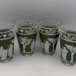May include: Four clear glass tumblers with a dark green band featuring white classical figures, trees, and decorative patterns. The glasses have a vintage aesthetic, suitable for serving beverages.