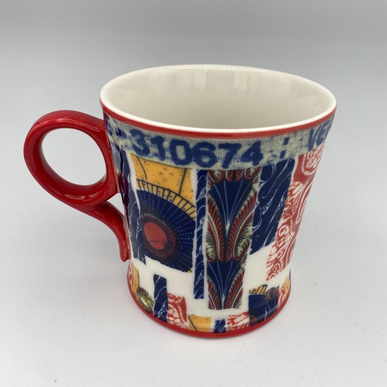 K&ouml;nnte beinhalten: Eine rote und wei&szlig;e Keramiktasse mit einem bunten geometrischen Muster und den Zahlen "310674" auf der Seite.
