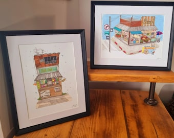 May include: Two framed watercolor paintings of street scenes in Southeast Asia. The left painting shows a small shop with the text "Fresh Fruit & Juice" and "Eat, Drink & Live" in a white frame. The right painting shows a larger shop with the text "Curry" in a black frame.