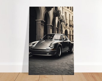 May include: A silver grey classic Porsche 911 sports car parked on a cobblestone street in front of an old building with arched doorways.
