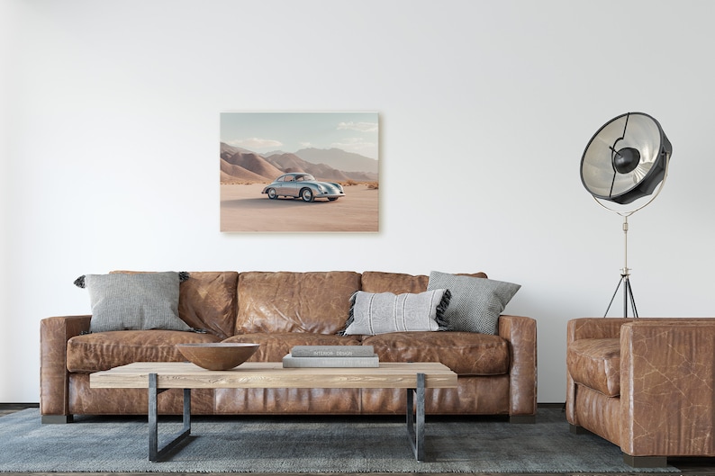 An original color car poster featuring the iconic Porsche 356 in silver in a desert. Available in  multiple sizes with free shipping. Pictured in a frame above a sofa. (frame not included)