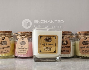 May include: Five glass jars with cork lids and twine accents, each containing a soy candle. The candles are labeled with the scents Honeysuckle, On Jasmine Wings, Lily & Jasmine, Green Fresh, and Mystic Musk. The jars are arranged in a row on a white surface. The label on the center jar reads "Soybean Candle".