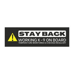 May include: A rectangular black sign with white text and a yellow warning symbol. The sign reads "STAY BACK WORKING K-9 ON BOARD TEMPERATURE MONITORED & CHECKED REGULARLY". The sign is designed to alert others of a working dog.