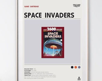 May include: A framed poster with a white background and black text. The poster features a vintage video game cartridge box for Space Invaders. The box is red, white, and blue with a picture of a spaceship. The text on the poster includes the game title, release year, platform, designer, developer, and objective.
