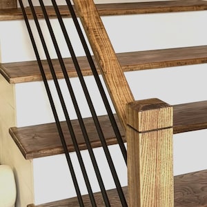 May include: A wooden staircase with white risers and dark wood treads. Black metal vertical balusters provide a modern contrast to the natural wood handrail and newel post. The design is a blend of traditional and contemporary styles.