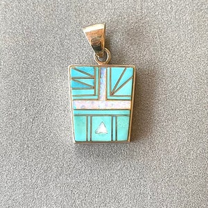May include: A turquoise, white, and gold pendant with a geometric design. The pendant is made of silver and has a triangular stone in the center.